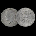 Two sides of a Kennedy Half Dollar coin on a black background