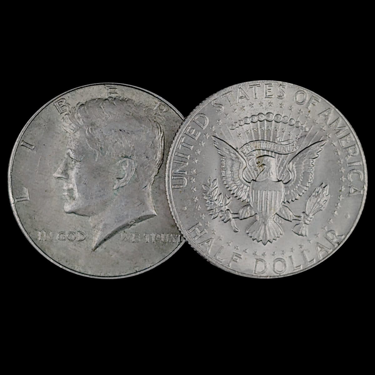 Two sides of a Kennedy Half Dollar coin on a black background