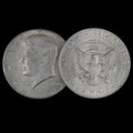 Two sides of a Kennedy Half Dollar coin on a black background