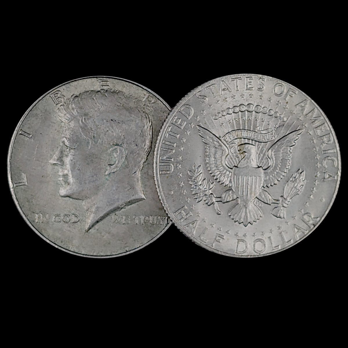 Two sides of a Kennedy Half Dollar coin on a black background